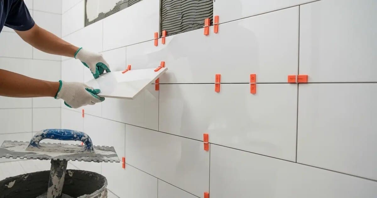 Craftsman installing subway tile on a bathroom shower wall with precision tools