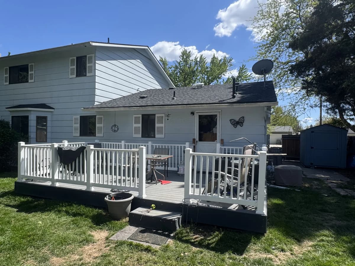 Rear of a Boise two-story home with old white siding and shutters before siding replacement
