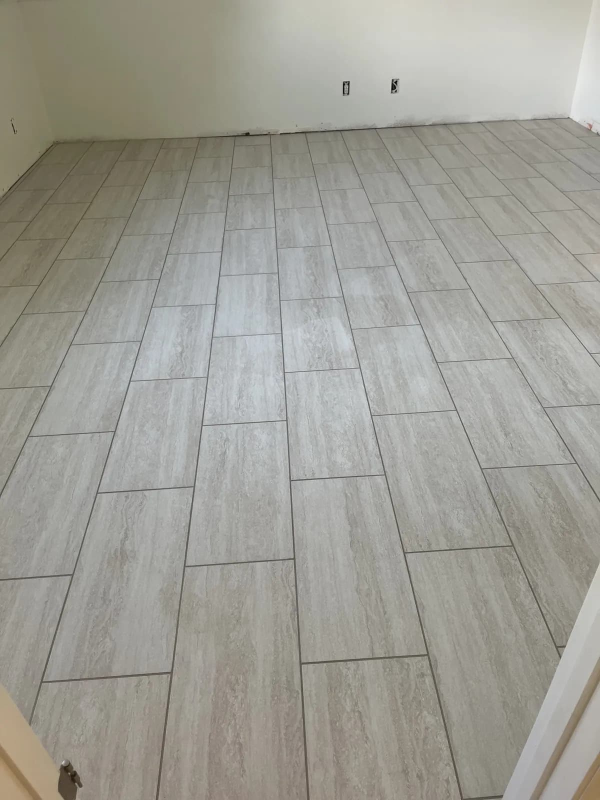 New gray plank-style tile floor in a staggered pattern in a Meridian basement room