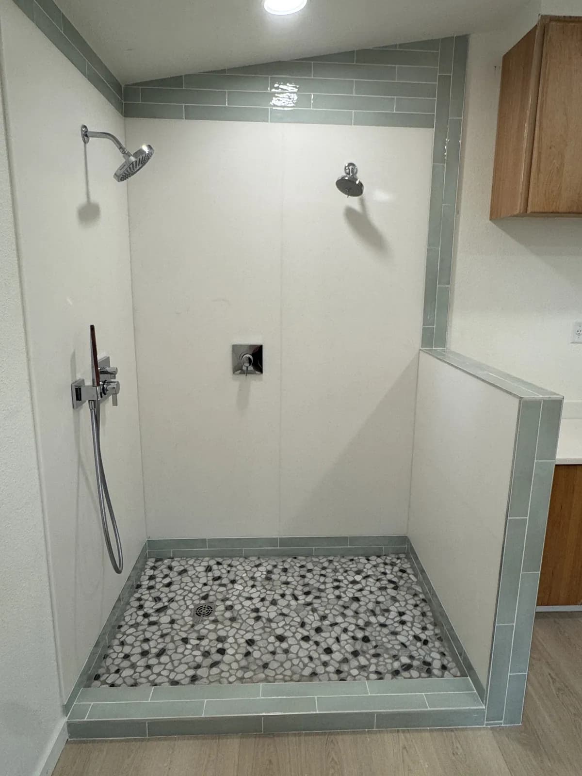 Finished walk-in shower in Mountain Home with pebble tile floor, new curb and accent tile bands