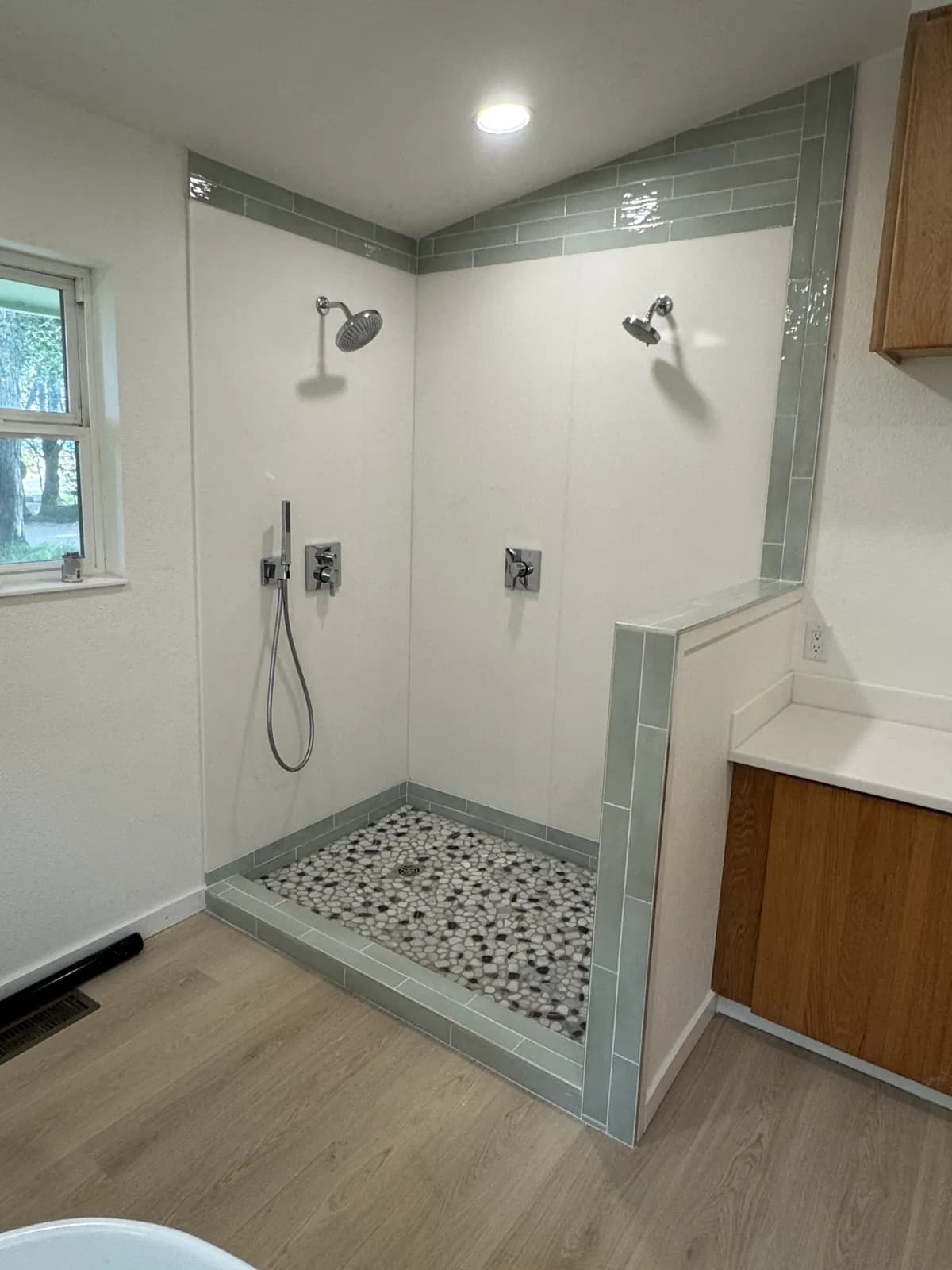 Completed Mountain Home walk-in shower with tiled half wall, pebble floor and wall panels