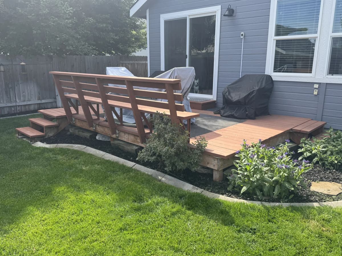 Old painted wood deck with a built-in bench and wood steps behind a Boise home before replacement